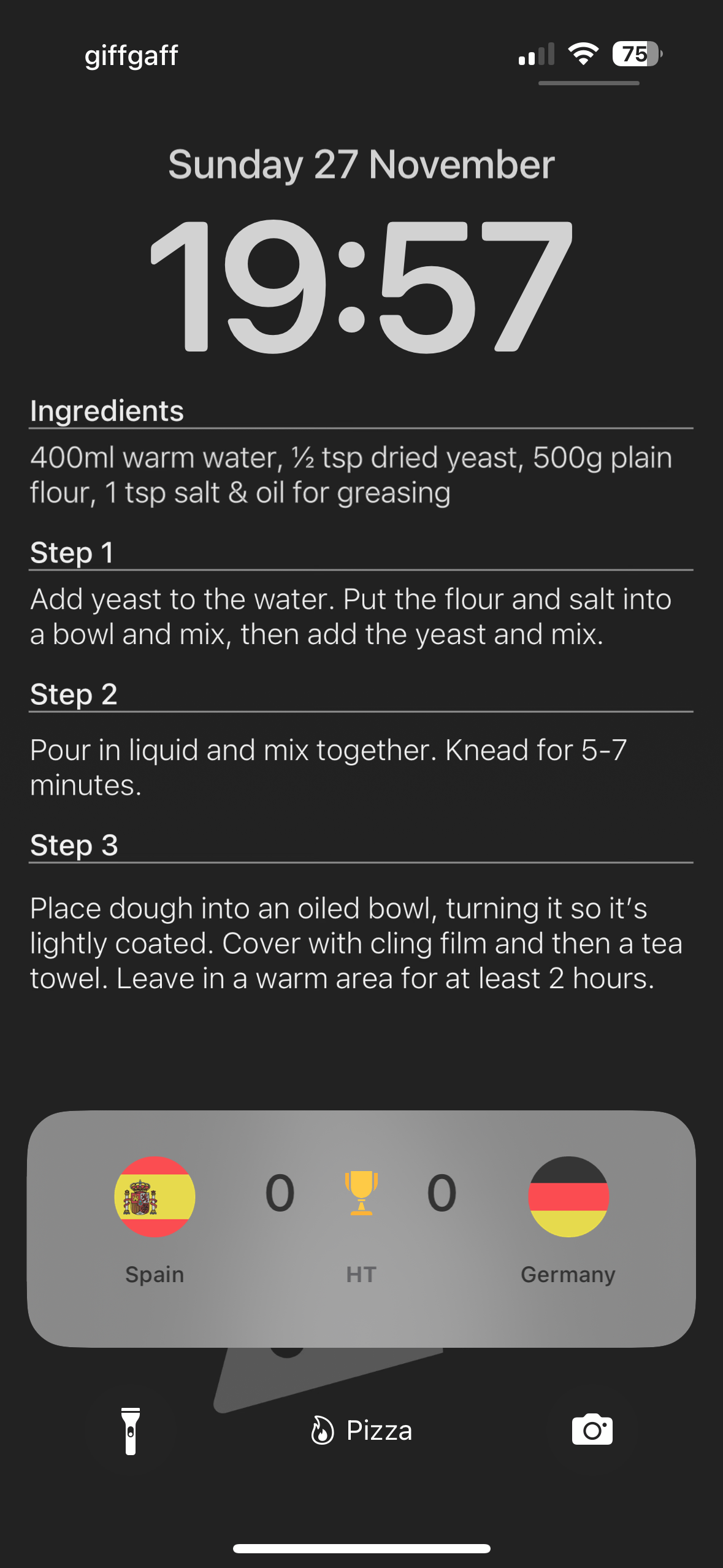 Screenshot of an iPhone 14 Pro with a wallpaper showing a basic pizza dough recipe. The screen also has a Live Activity from the 2022 World Cup of a match between Spain and Germany. The text for the recipe is formatted in such a way that it does not interfere with the Live Activity.